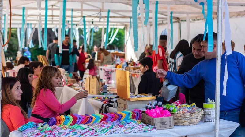 Puesto con productos coloridos y compradores en una feria de emprendedores, ejemplo ilustrativo de exhibición comercial