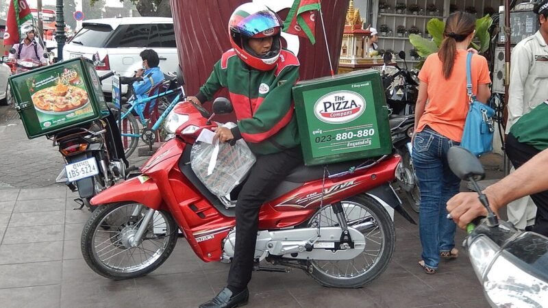 Repartidor en motocicleta durante una entrega, fotografía ilustrativa tomada fuera de Colombia