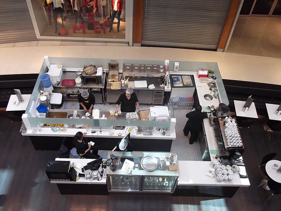Vista ilustrativa de una cafetería con mesas y área de atención
